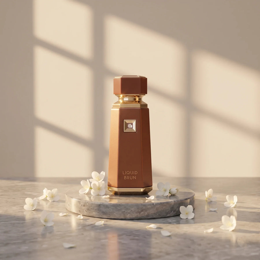 French Avenue Liquid Brun brown perfume bottle on a stone display with white flowers