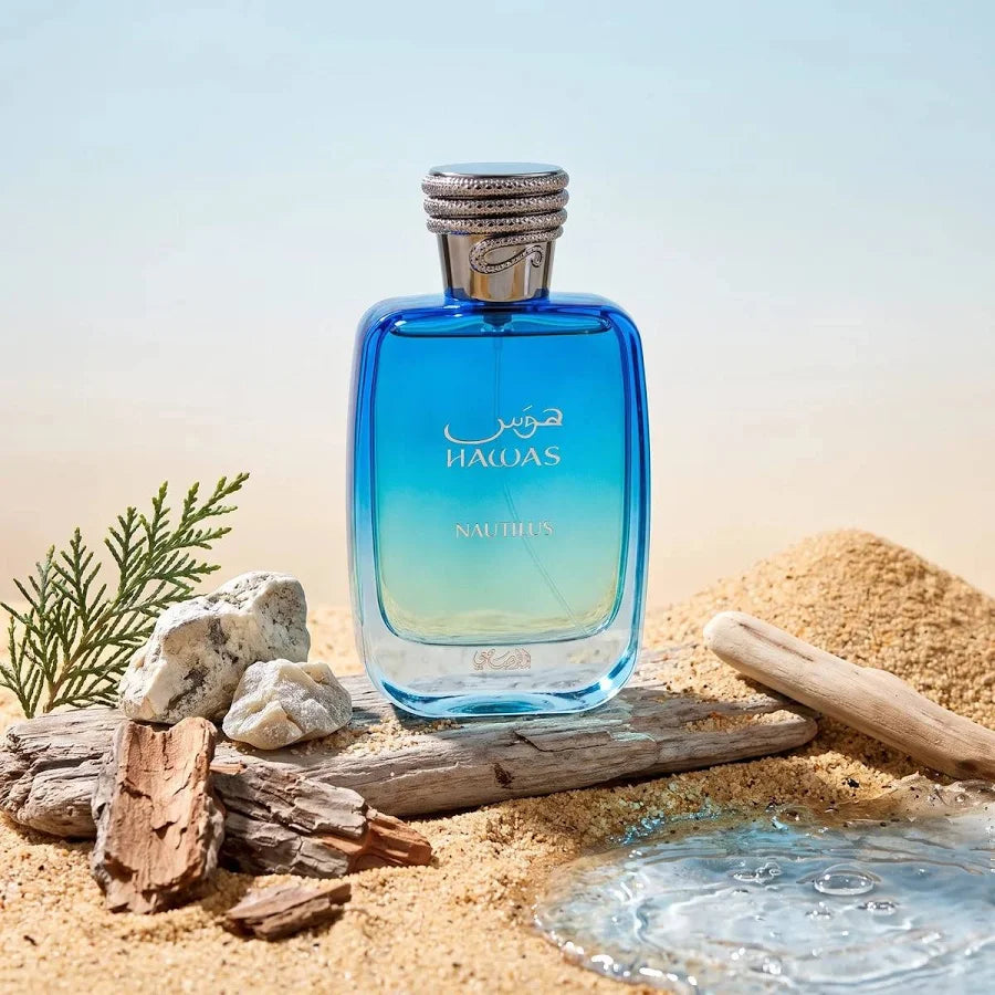 Rasasi Hawas Nautilus perfume bottle displayed with driftwood, sand and water